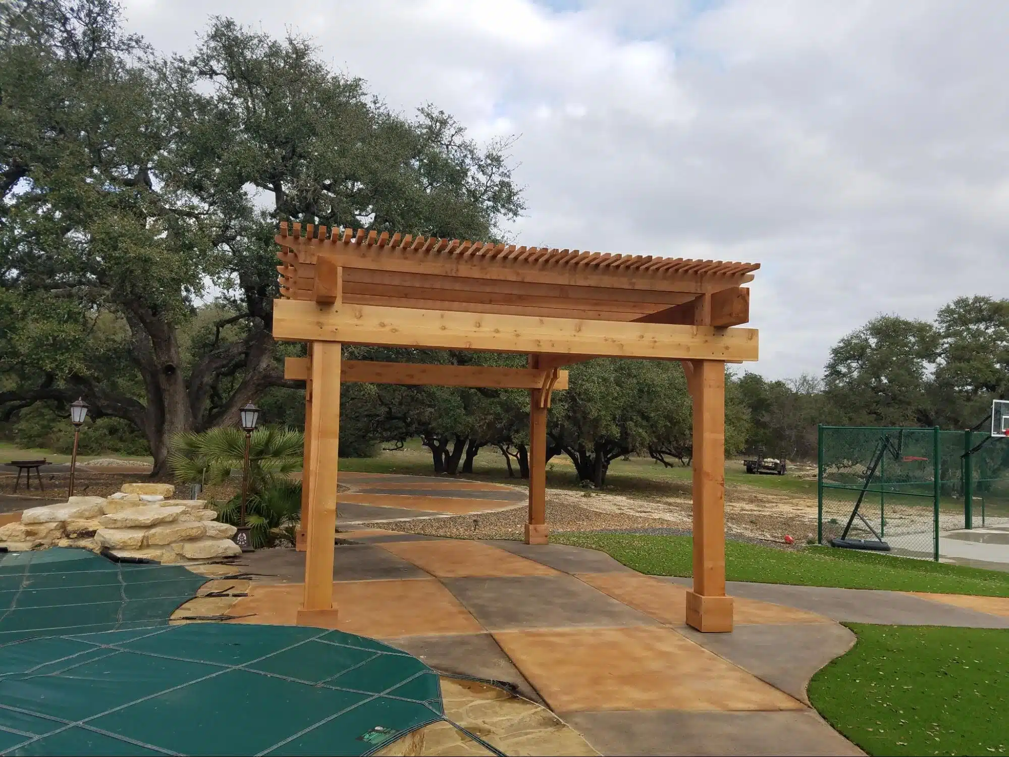 Photo of a wooden pergola surrounded by trees.